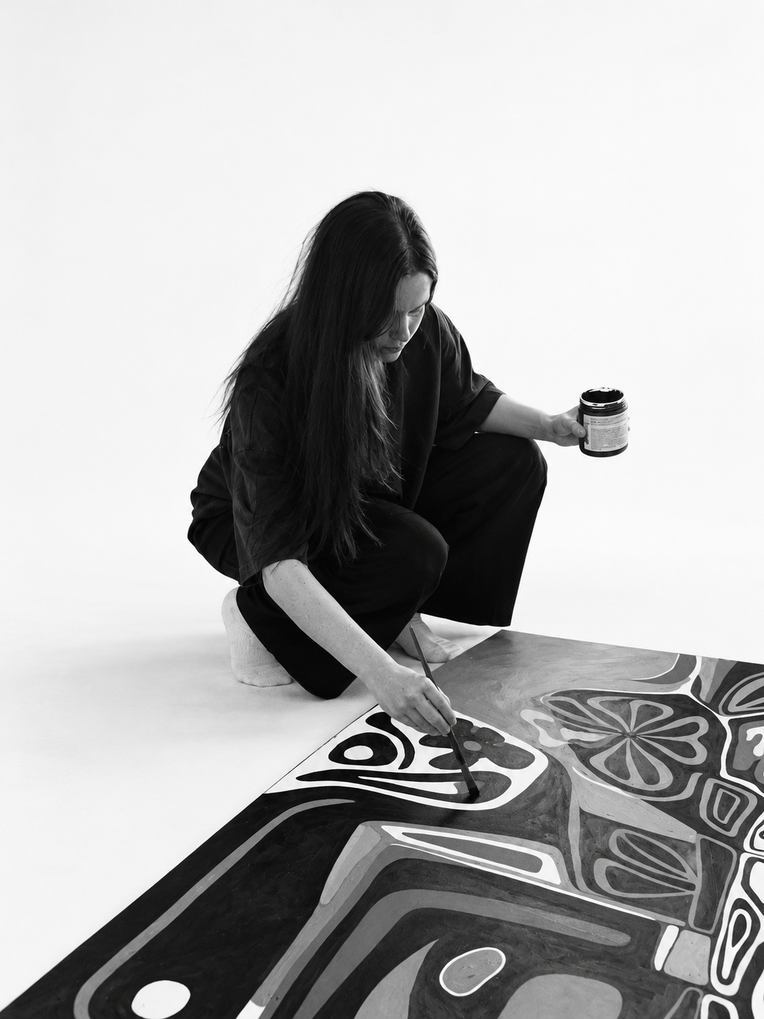 Genny Nugent painting on the studio floor, photographed in black and white