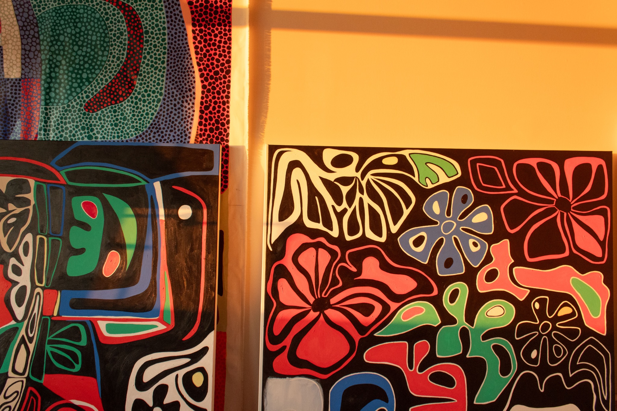 Paintings leaning against a studio wall in golden sunlight